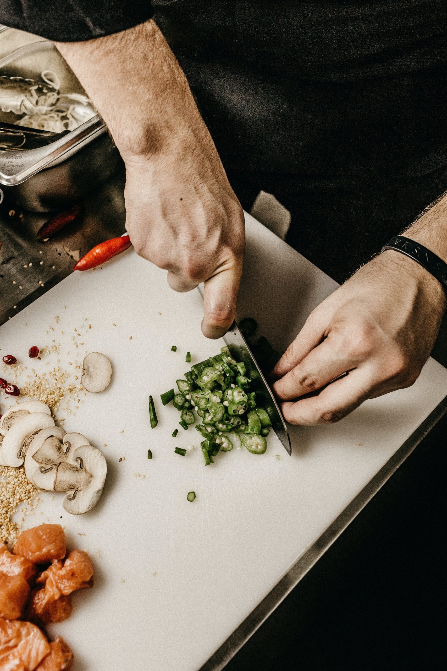 Bilden visar en person som hackar mat på en skärbräda. Restaurangmaskiner är även en viktig del för att förbereda mat i ett kök och underlätta matlagningen.